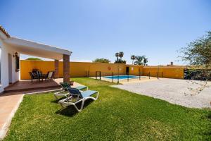 un patio trasero con piscina y césped en Luisa 1 en Conil de la Frontera