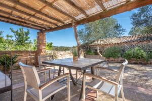 a patio with a table and chairs under a wooden pergola at Es Rafal Roig - Es Cestador in Sant Llorenç des Cardassar