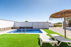 a swimming pool with two chairs and an umbrella at Casa Palillero - Sólo Familias in Conil de la Frontera