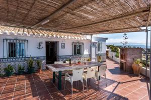 un patio esterno con tavolo e sedie in legno di Casa del Pipa con vistas al mar a Benajarafe