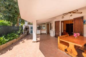 eine Terrasse mit einem Holztisch und einer Küche in der Unterkunft Casa Marisol in Quartu SantʼElena