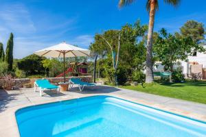 una piscina con sillas, una sombrilla y un parque infantil en Sa Creu De Saume, en Artà