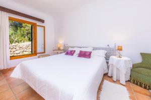ein Schlafzimmer mit einem großen weißen Bett und einem grünen Stuhl in der Unterkunft Sa Creu De Saume in Artá + 29 Fotos