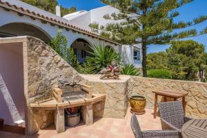a patio with a stone wall and a table and chairs at Shangri-la in Santa Eularia des Riu