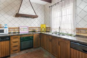 a kitchen with wooden cabinets and a sink and a window at Casa Familiar La Lobita 1 in Conil de la Frontera