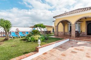 a home with a patio and yard with palm trees at Casa Familiar La Lobita 1 in Conil de la Frontera