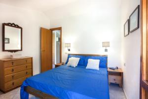 - une chambre avec un lit bleu et une commode en bois dans l'établissement Villa Vanna, à Villasimius