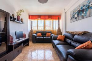 uma sala de estar com um sofá e uma televisão em Apartamento Mariam em Málaga