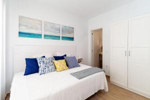 a white bedroom with a white bed with blue pillows at Apartamento Luna in Barbate