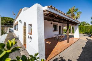 a white house with a wooden roof and a patio at Cortijo Entrepinares in Conil de la Frontera