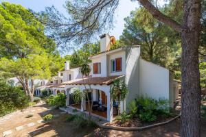 einen Blick auf ein weißes Haus mit Bäumen in der Unterkunft Can Botana 1 in Cala de Sant Vicent