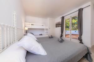 ein Schlafzimmer mit einem Bett mit weißen Kissen und einem Fenster in der Unterkunft Can Botana 1 in Cala de Sant Vicent