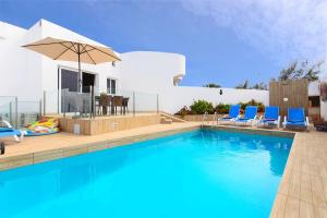 una piscina con sillas y una sombrilla junto a una casa en Villa Xana, en Playa Blanca