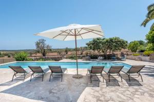 a group of chairs and an umbrella next to a pool at Son Xigala in Manacor