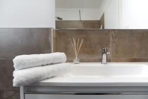 a bathroom with a white sink and towels at Appartamenti Dama 2 in Bardolino +17 photos