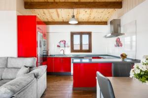 a kitchen with red cabinets and a couch at Casa Hefestión in Conil de la Frontera