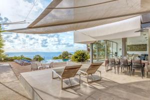 un patio esterno con tavoli, sedie e vista sull'oceano di Villa Es Pas a El Estanyol