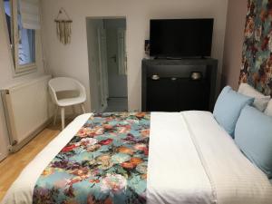 Un dormitorio con una cama con una manta floral. en La Petite Maison de Jane en Reims