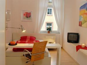 1 dormitorio con escritorio, 1 cama y ventana en Pension Müllers Alte Backstube en Reichenbach im Vogtland