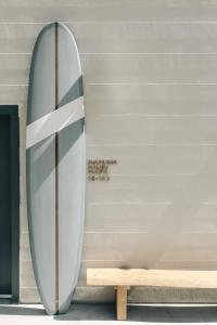 una tabla de surf apoyada en una pared junto a un banco en The Surfrider Malibu, en Malibú