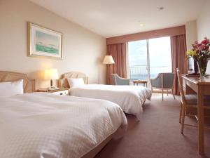 a hotel room with two beds and a desk at Yumihari-no-Oka Hotel in Sasebo