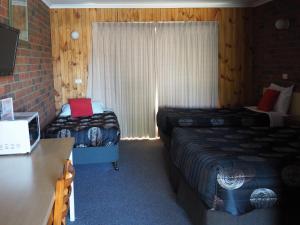 a hotel room with two beds and a desk with a laptop at Country Road Motel St Arnaud in Saint Arnaud