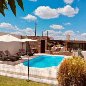 una piscina con sombrillas y sillas junto a una casa en Loft & Wines en Maipú