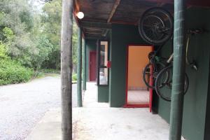 a building with a bike hanging on the side of it at Riverbank Retreat in Rai Valley