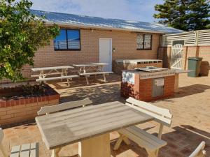 a picnic table and benches in front of a building at Ocean Beach Chalet 18 in Jurien Bay