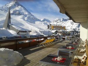 eine Terrasse mit Tischen, Stühlen und einem Berg in der Unterkunft Alpenhotel Seiler in Kühtai