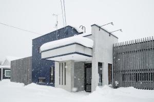 a building covered in snow in front of a building at Jstyle STAY Furano in Furano