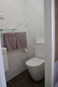 a white bathroom with a toilet and a towel at Carnarvon Lodge Kirribilli, Sydney in Sydney