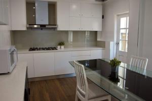 a kitchen with white cabinets and a glass table at Carnarvon Lodge Kirribilli, Sydney in Sydney