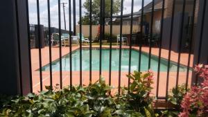 a pool with a fence and a tennis court at Shady Rest Motel in Gympie