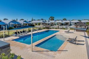 a swimming pool with chairs and umbrellas in a resort at Seafront Unit 49 in Jurien Bay