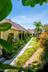 a resort with a pathway and palm trees and plants at Ocean Sun Dive Resort in Tulamben
