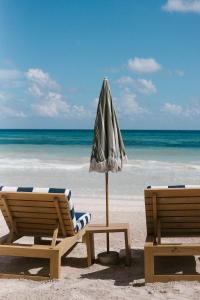 two chairs and an umbrella on the beach at Hotel Panamera in Tulum