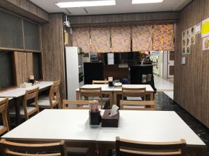 a dining room with tables and chairs and a person at Kokusai Towns Inn in Naha