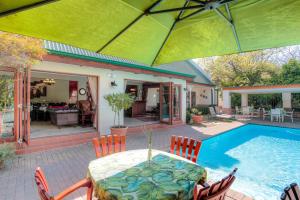 Un patio con mesa y sillas junto a una piscina. en Sunninghill Guest Lodges, en Johannesburgo