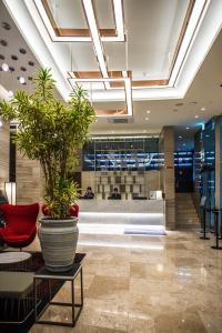 a lobby with a large potted plant in a building at Ramada Encore by Wyndham Busan Station in Busan