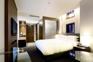 a hotel room with a bed and a glass table at Ramada Encore by Wyndham Busan Station in Busan
