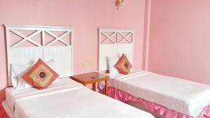 two beds in a room with pink walls at Sri Chumphon Hotel in Chumphon