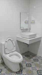 a white bathroom with a toilet and a sink at Sri Chumphon Hotel in Chumphon