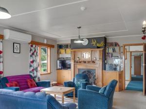 a living room with blue chairs and a fireplace at Surat Bay Lodge, Motel and Backpackers in Owaka