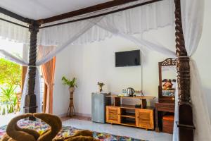 a bedroom with a bed and a tv on the wall at Pondok Wisata Sartaya 2 in Lovina