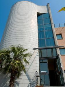 un edificio con una palmera delante de él en Mini Hotel, en Asti