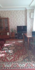 a living room with a table and a television at Guest House OTILIA in Gyumri