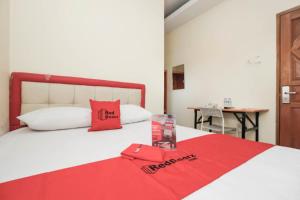 a bed with a red blanket on top of it at RedDoorz Plus @ Jalan Pemuda Jakarta in Jakarta