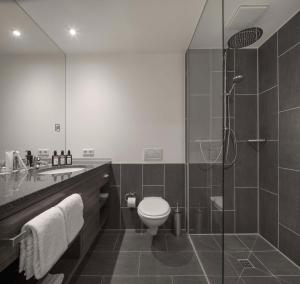 La salle de bains est pourvue de toilettes et d'une douche en verre. dans l'établissement Factory Hotel, à Münster