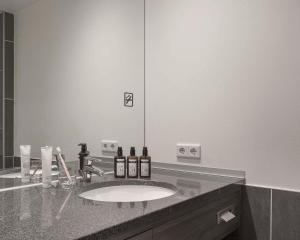 ein Badezimmer mit einem Waschbecken und einem großen Spiegel in der Unterkunft Factory Hotel in Münster